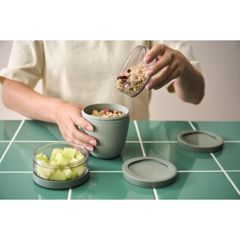 Personne utilisant un pot repas isotherme vert avec compartiments ouverts, sans marquage visible sur les zones observables.