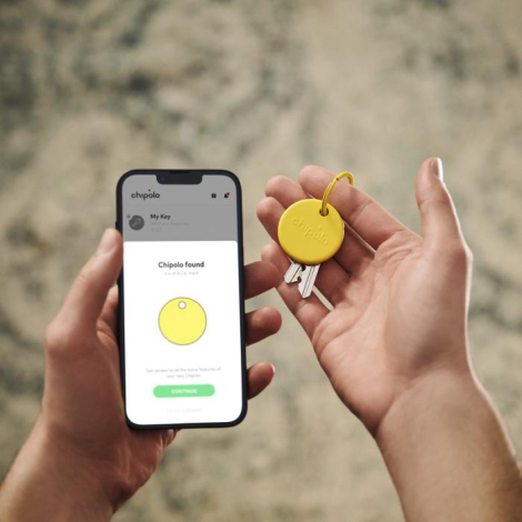 Personne tenant une balise jaune attachée à des clés en situation, sans marquage visible sur le produit.