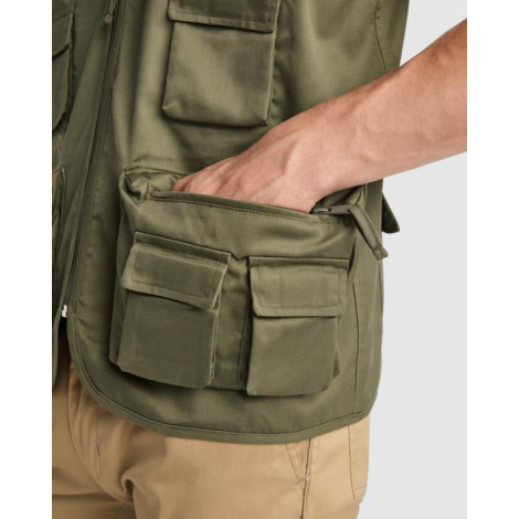 Zoom sur les poches cargo et la poche zippée d’un gilet de travail kaki porté, illustrant les compartiments de rangement et les 