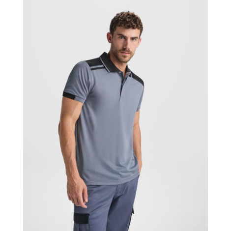 Polo unisexe gris avec empiècements noirs aux épaules porté par un homme, présenté de trois quarts sans personnalisation apparen