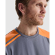 Zoom sur le haut d’un t-shirt homme gris avec empiècements orange aux épaules et bandes contrastées, porté par un homme sans mar Zoom sur le haut d’un t-shirt homme gris avec empiècements orange aux épaules et bandes contrastées, porté par un homme sans mar