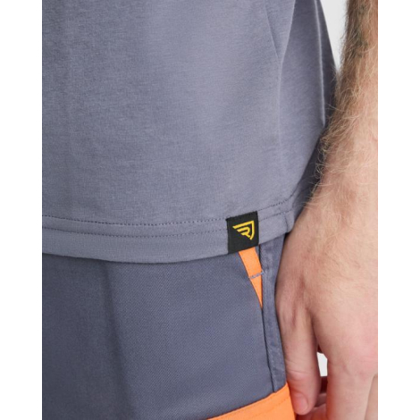 Zoom sur le bas d’un t-shirt homme gris porté avec un pantalon de travail, mettant en avant la finition de l’ourlet latéral et u