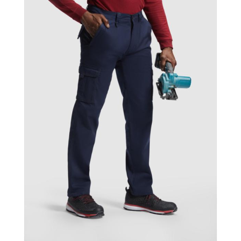 Homme portant un pantalon de travail bleu marine de trois quarts tout en tenant un outil électroportatif, avec poches cargo fonc