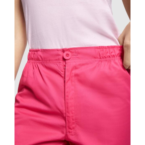Zoom sur la ceinture élastiquée et la fermeture boutonnée d’un pantalon de service rose, porté sans marquage visible.