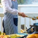 Femme portant un tablier de cuisine à rayures bleu foncé et blanches en situation de cuisson, sans marquage apparent. Femme portant un tablier de cuisine à rayures bleu foncé et blanches en situation de cuisson, sans marquage apparent.