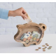 Tirelire en situation d’utilisation avec billets et pièces visibles à l’intérieur, sans personnalisation apparente. Tirelire en situation d’utilisation avec billets et pièces visibles à l’intérieur, sans personnalisation apparente.