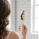 Femme tenant la brosse à peluches avec miroir ouvert et observant son reflet.