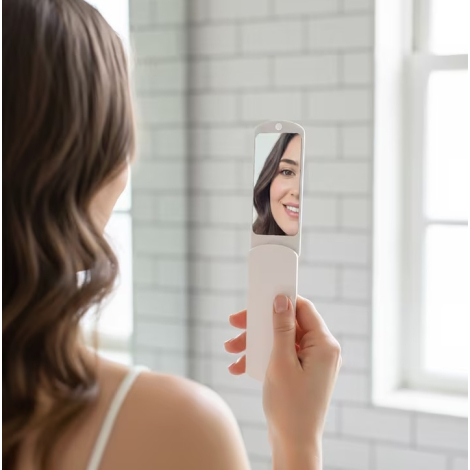 Femme tenant la brosse à peluches avec miroir ouvert et observant son reflet.