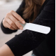 Femme utilisant la surface textile de la brosse à peluches sur la manche d’un vêtement foncé.