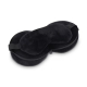 Masque de sommeil noir disposé sur une housse de rangement ouverte, sans marquage apparent.