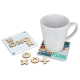 Sous-verre utilisé sous une tasse tandis que le plateau de jeu et plusieurs pièces en bois sont disposés à côté.