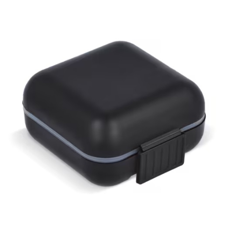 Boîte à pilules compacte noire fermée avec couvercle présenté sans marquage apparent.