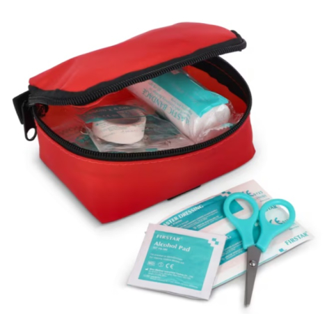 Vue rapprochée d’une trousse de secours rouge ouverte avec plusieurs accessoires visibles à l’intérieur, dont des compresses et 