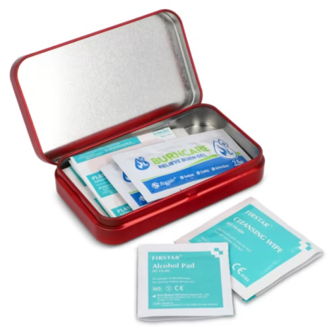 Boîte métallique de premiers secours ouverte avec plusieurs pansements et sachets de soin visibles à l’intérieur, ainsi que quel