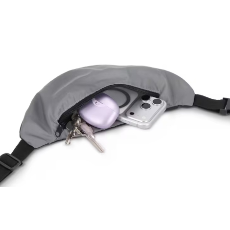Sac banane réfléchissant Zola ouvert, montrant l’intérieur contenant un smartphone, un boîtier d’écouteurs et un trousseau de cl