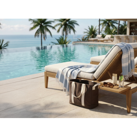 Sac de plage utilisé au bord d’une piscine, posé à côté d’un transat, sans personnalisation apparente.
