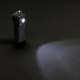 Porte-clés alarme posé sur une surface sombre avec éclairage LED activé, projetant un faisceau lumineux. Porte-clés alarme posé sur une surface sombre avec éclairage LED activé, projetant un faisceau lumineux.