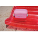 Glacière rose posée sur une bouée gonflable rouge sur une plage. Le couvercle est visible sans personnalisation apparente. Glacière rose posée sur une bouée gonflable rouge sur une plage. Le couvercle est visible sans personnalisation apparente.