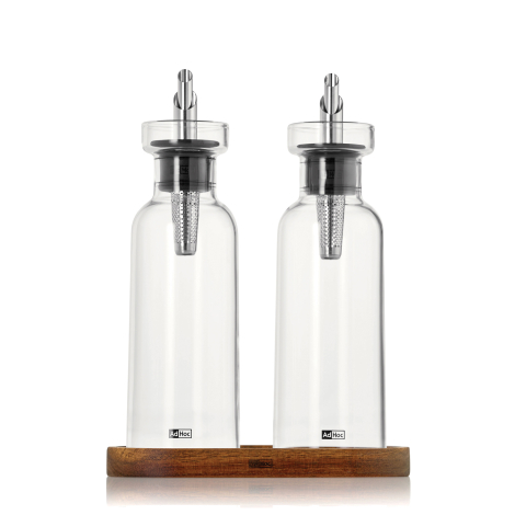 Ensemble huile et vinaigre composé de deux bouteilles en verre avec becs verseurs métalliques, présenté sur son support en bois,