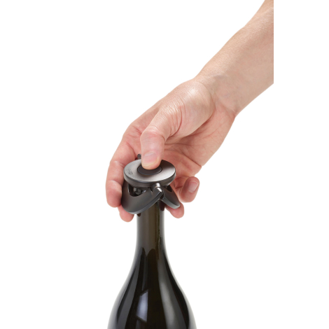 Main manipulant le bouton supérieur du bouchon installé sur une bouteille.