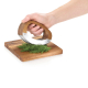 Main utilisant le hachoir à lame courbe sur un lit d’herbes fraîches posé sur la planche en bois. Main utilisant le hachoir à lame courbe sur un lit d’herbes fraîches posé sur la planche en bois.