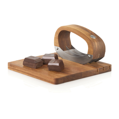 Ensemble hachoir avec planche présenté avec des morceaux de chocolat déposés sur la planche.