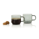 Lot de deux tasses expresso en verre fumé avec anse, dont une remplie de café. Deux biscuits sont placés à côté. Les deux tasses