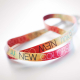 Gros plan sur une sangle de lanyard avec impression multicolore en sublimation et texte visible sur toute la surface Gros plan sur une sangle de lanyard avec impression multicolore en sublimation et texte visible sur toute la surface