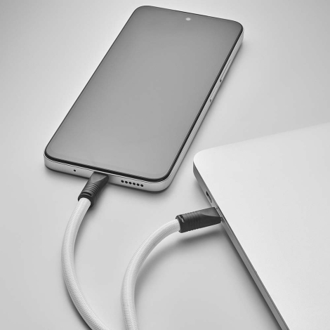 Câble de charge intégré à gaine textile blanche reliant un smartphone à un ordinateur portable sans personnalisation visible