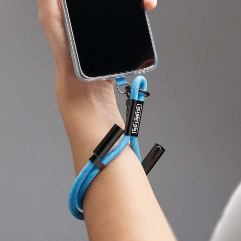 Dragonne bleue avec câble de charge intégré portée au poignet et reliée à un smartphone, avec marquage texte visible sur l’embou