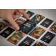 Main manipulant un étui de jeu de cartes personnalisé posé au milieu de cartes illustrées présentant différents graphismes visib Main manipulant un étui de jeu de cartes personnalisé posé au milieu de cartes illustrées présentant différents graphismes visib