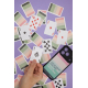 Cartes de jeu étalées présentant les valeurs traditionnelles sur une face et un graphisme imprimé sur l’autre, à côté d’un smart Cartes de jeu étalées présentant les valeurs traditionnelles sur une face et un graphisme imprimé sur l’autre, à côté d’un smart