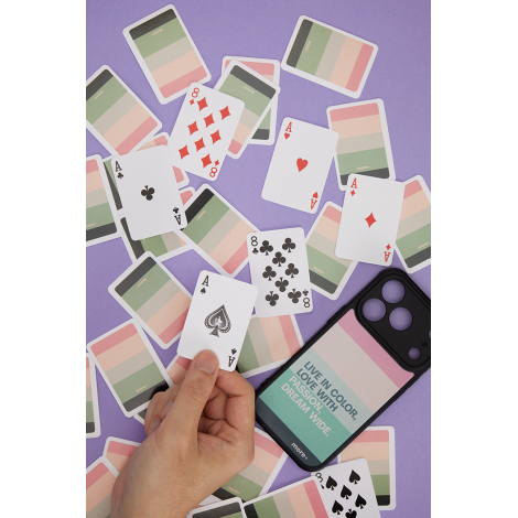Cartes de jeu étalées présentant les valeurs traditionnelles sur une face et un graphisme imprimé sur l’autre, à côté d’un smart