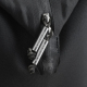 Gros plan sur les curseurs métalliques de la fermeture zippée et la tirette siglée du sac noir.