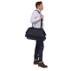 Homme portant le sac de voyage à l'épaule grâce à la bandoulière, sans personnalisation visible. Homme portant le sac de voyage à l'épaule grâce à la bandoulière, sans personnalisation visible.