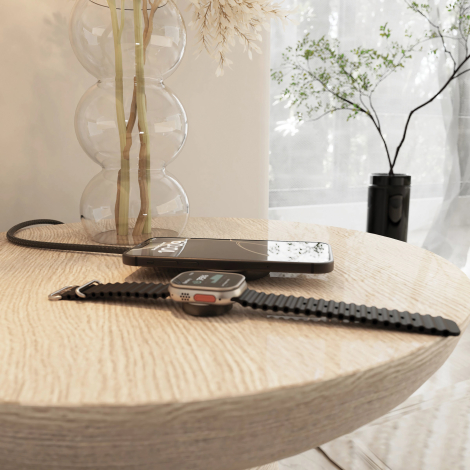 Câble de recharge utilisé sur une table avec un smartphone et une montre connectée en cours de charge dans un environnement inté