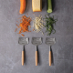 Trois tranchettes à fromage alignées sous différents légumes et fromages râpés, sans marquage visible. Trois tranchettes à fromage alignées sous différents légumes et fromages râpés, sans marquage visible.