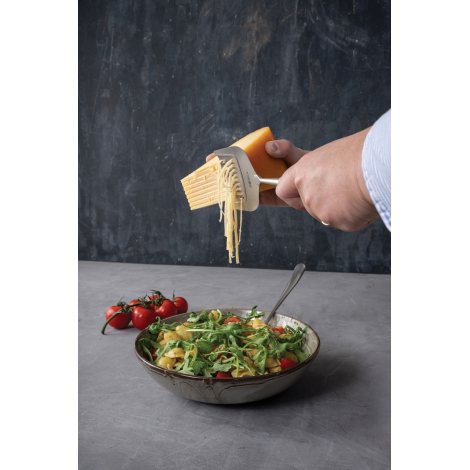 Personne utilisant la tranchette à fromage pour découper de fines lamelles au-dessus d’une salade, sans personnalisation visible
