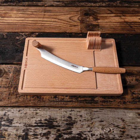 Coupe-fromage posé sur sa planche en bois sur une table rustique, sans personnalisation visible sur la planche.