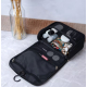 Trousse de toilette noire ouverte avec accessoires rangés dans les compartiments, sans personnalisation visible. Trousse de toilette noire ouverte avec accessoires rangés dans les compartiments, sans personnalisation visible.