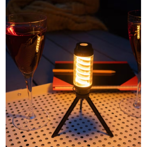 Lampe allumée utilisée comme éclairage d’ambiance sur un mini trépied, posée sur une table dans un environnement faiblement écla