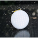 Lampe allumée présentée sous la pluie, mettant en avant sa face lumineuse circulaire dans un environnement humide.