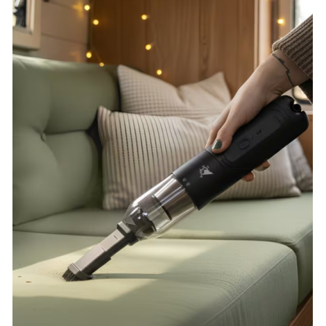 Mini aspirateur souffleur utilisé avec un embout fin pour nettoyer un canapé, sans marquage visible.