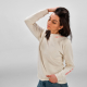 Une femme porte un sweat à col rond écru présenté de trois quarts de devant, avec un marquage visible au niveau du col et sur la