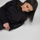 Une femme porte un sweat à col rond noir avec un marquage visible au niveau du col et sur la manche gauche.