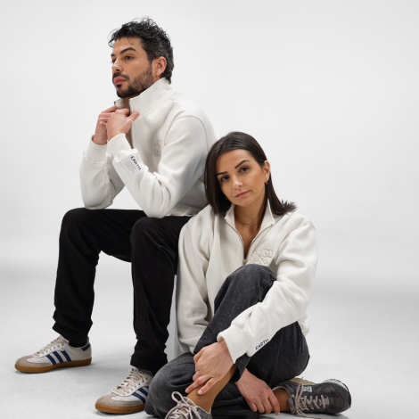 Sweats à col montant avec demi-zip portés par un homme et une femme, avec des marquages visibles sur la poitrine et sur le bas d