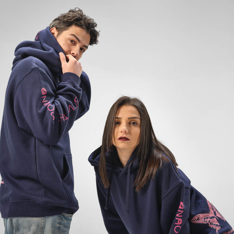 Sweats à capuche portés par un homme et une femme, avec des inscriptions et des motifs visibles sur les manches, la capuche et l