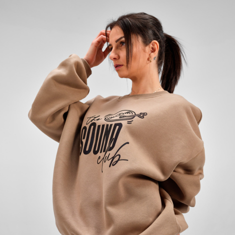 Sweat oversize porté par une femme, avec un graphisme et une inscription visibles sur le devant.