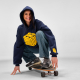 Femme portant un sweat à capuche oversize bleu marine avec un marquage visible sur le devant et en bas de la manche gauche, accr