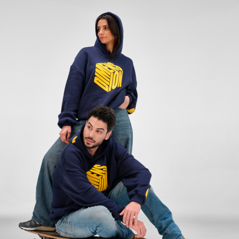 Un homme et une femme portent un sweat à capuche oversize bleu marine avec un marquage visible sur le devant, une épaule, la cap
